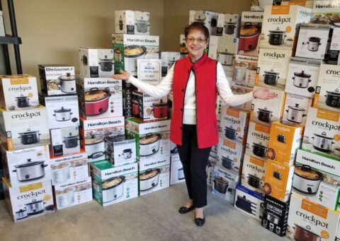 Executive Director, Sandy Harley, poses in front of crock pot donations