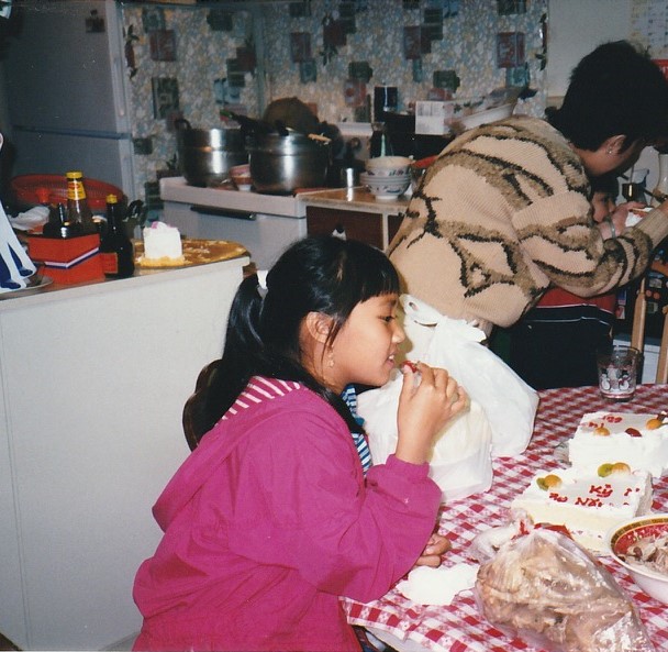 a young Marria sits at a table and eats food with her family