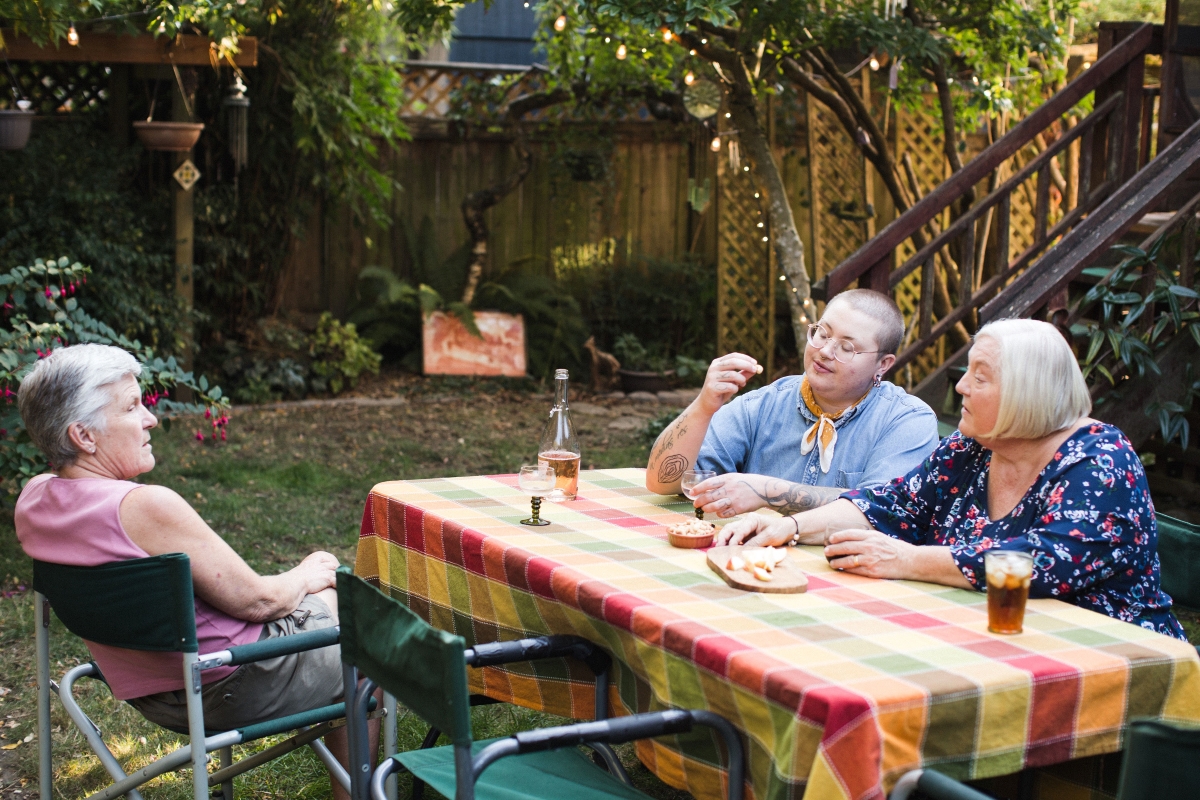 Family of three gathers outside around table with snacks and drinks